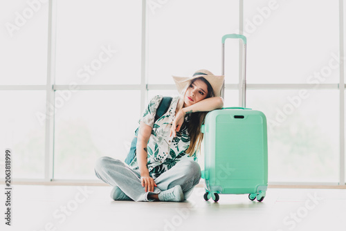 Obraz na plátně Sad woman leaning on suitcase in airport terminal, enjoying casual travel attire