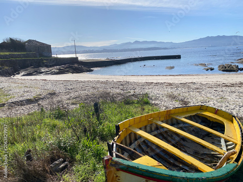 Fényképezés A vibrant fishing boat sits on a tranquil beach, its paint chipped from years of sun and sea