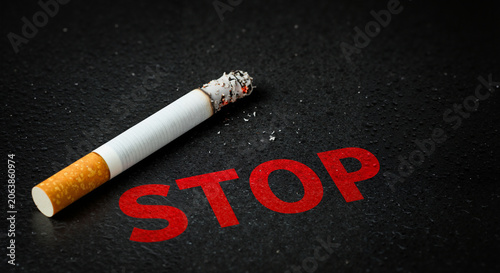 Cigarette extinguished with red stop message on dark background  