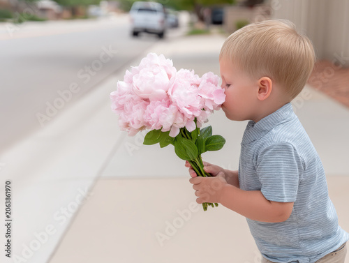 Cute toddler boy practicing mindfulness, gently smelling pink flower bouquet. An innocent child enjoys calm and peaceful