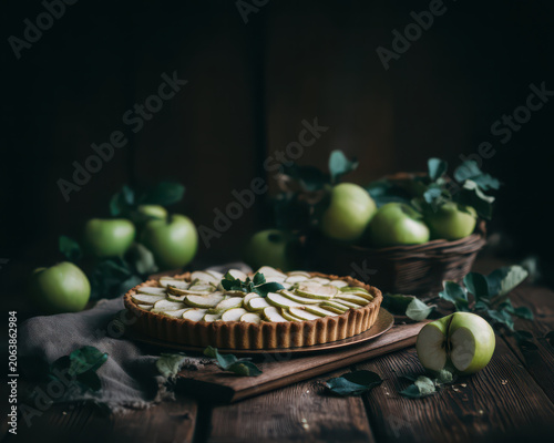 Cozy rustic apple pie, delicious homemade dessert. Fresh green fruit on dark wooden table background for comfort food