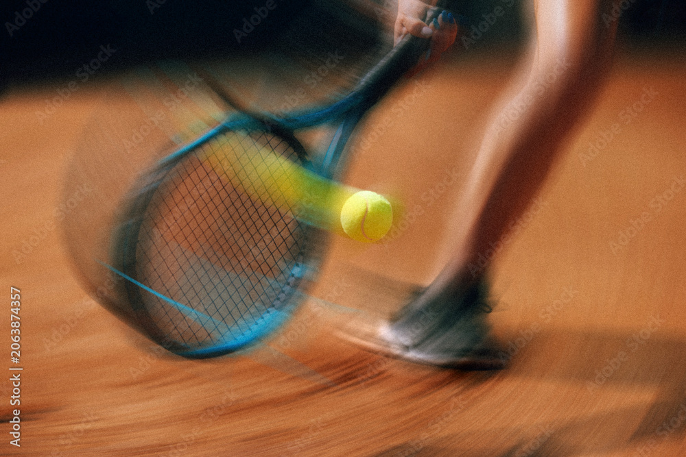 Naklejka premium Tennis racket striking ball with dynamic motion blur on court. Concept of tennis action poster, speed and motion blur, athletic competition, dynamic sports advertising.