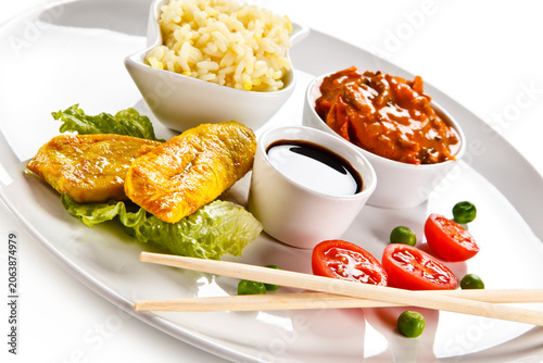 Fried chicken nuggets, white rice and vegetables on white background
