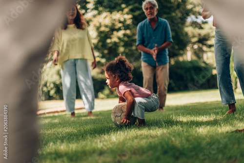 Multi-generational family playing soccer in park