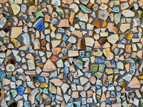 Many broken pieces of antique pottery and ceramic fragments arranged as an intricate mosaic pattern, forming a unique background texture - stock photo