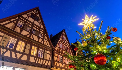 A low-angle shot of a festively decorated Christmas tree standing in front of traditional half-timbered houses at dusk