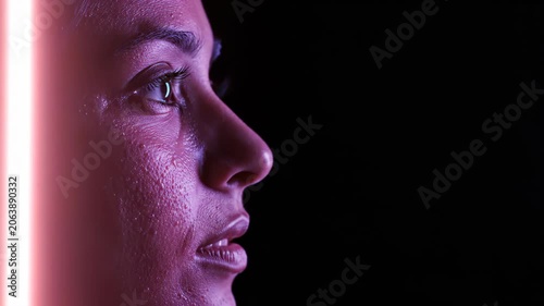 Woman profile view illuminated by shifting neon light. Side portrait reflecting transition between blue and red color spectrums. Digital data analysis concept