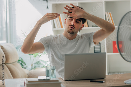 Quadro su tela young man at home studying and working on a laptop during a summer heat wave
