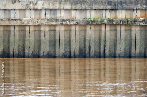 Fotografie Concrete embarkment structure for soil erotion control on the edge of murky brow