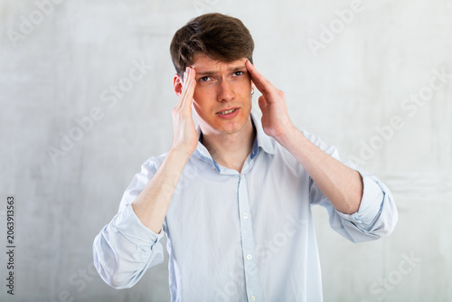 Young man experiencing acute headache in living room