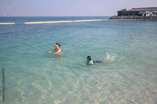 Asian woman and multiracial boy swimming in clear ocean water on