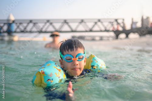 Playful Child Swimming in Shallow Water with Inflatable Arm Floaties