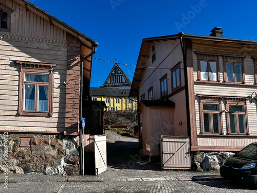 Traditional Old Wooden Finnish Houses on Medieval Street and Gable of Lutheran Cathedral in the Background in Porvoo (Borgå) Finland. 