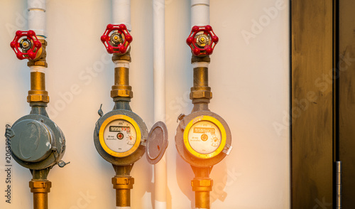 Fotografie Water meter installed on a brass pipe system outside a residential building