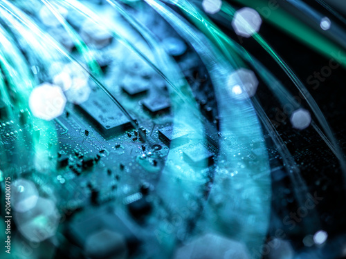 Close-up of a circuit board with glowing fibers and a futuristic blue-green hue.