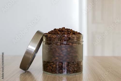 Glass jar filled coffee beans on a table. Preparing for brewing coffee.