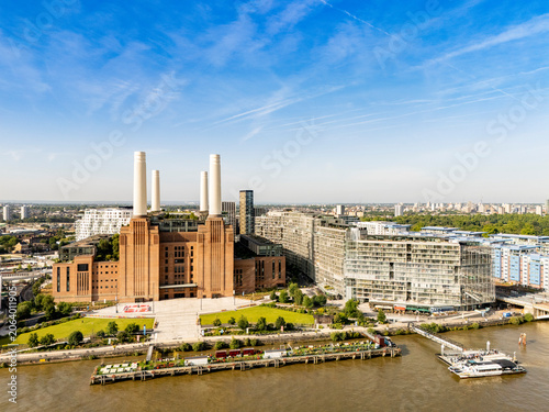 Obraz na plátne Aerial view of a large industrial building with tall chimneys by a river and modern buildings
