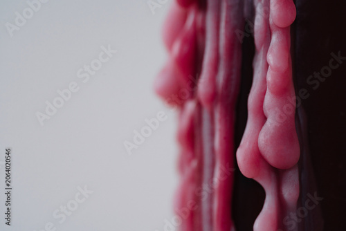 Close-up of melted red wax texture on a light background. Abstract detail showing organic shapes, flow, and material imperfection, suitable for symbolic, emotional, and conceptual uses.