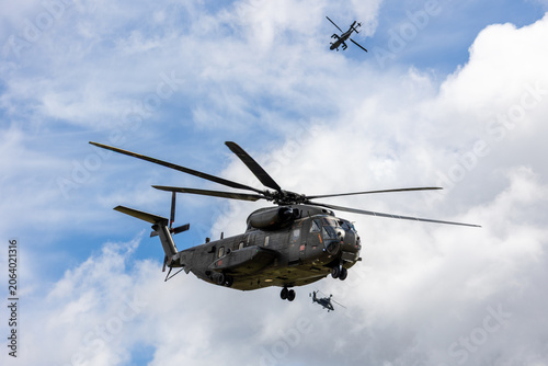 Billede på lærred Military transport helicopter flies cloudy sky accompanied attack helicopters formation