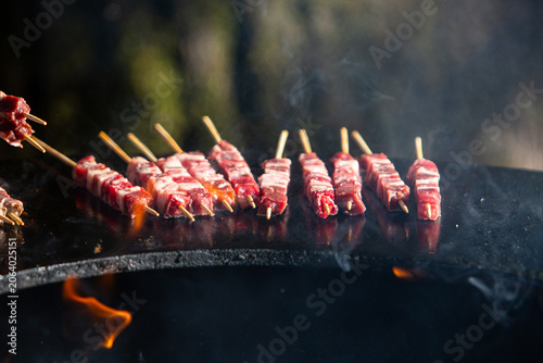 Cooking arrosticini skewers over hot charcoal grill fire