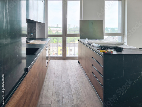 Installing modern black kitchen with dark cabinets, wood drawers, kitchen island
