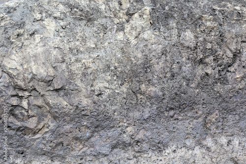 Close-up of coarse gray rock reveals intricate natural patterns and uneven surface.