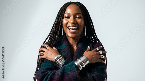 Studio fashion portrait of a joyful woman with braids and jewelry