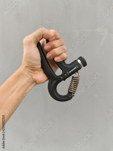 Foto Hand grips a fitness tool against plain gray wall