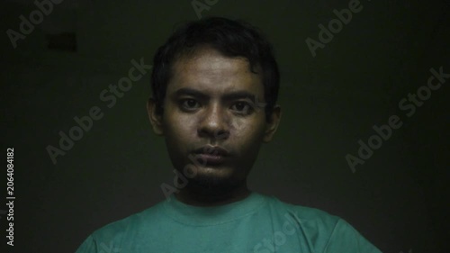Portrait Of A Young Asian Man Making Aggressive Threatening Gestures Against A Dark Green Background