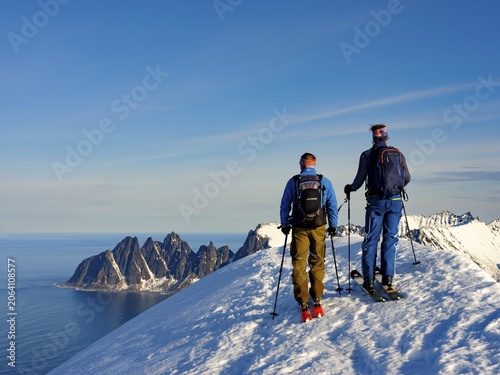 Two ski mountaineers at the summit of Husafjellet with a view over Devils Teeth, Okshornan, Senja Island, Troms, Norway
