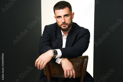 Handsome man in black suit on wooden chair