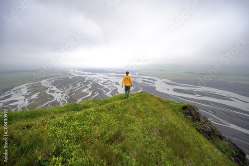 Hiker on a hill, view over alluvial land, river meandering, Dímonarhellir, Suðurland, Iceland