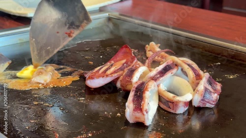 日本の鉄板焼き。イカ焼き。鉄板で焼いてる新鮮なイカ。イカ肝とバターと醤油を混ぜる動画。