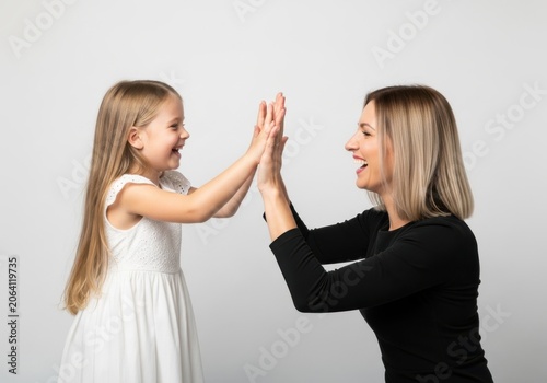 A young girl and a woman giving each other a high five while smiling at each other