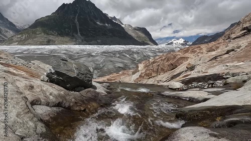 Glacial Meltwater Flowing Over Mineral Stained Reddish Rocks at Aletsch Glacier Valais Switzerland