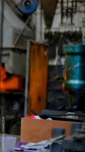 Vertical video: Panning camera showing box with tools on bench at shop, revealing forge, copy space