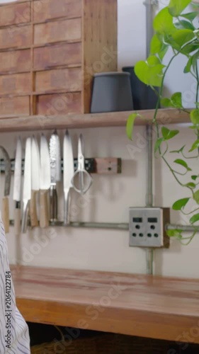 Vertical video: Leaning senior in striped tee placing cup on counter at home making tea, copy space