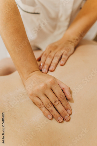 Close up of back massage therapy session. Female massage therapist's hands.