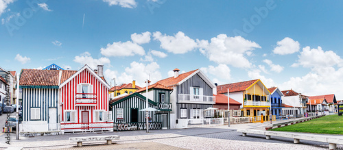 Iconic wooden houses with colorful vertical stripes under a clear blue sky in Costa Nova, Portugal.