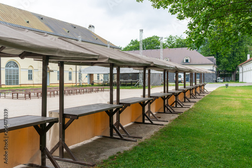 Bild auf Leinwand Covered market stands arranged in a row within a historic courtyard before opening hours