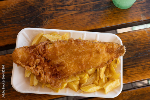 Fried fish served on a tray with golden chips in a casual dining setting at a seaside restaurant during the afternoon