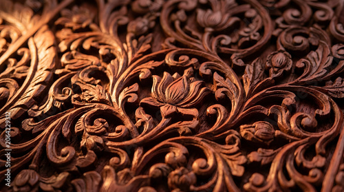 Macro close-up of hand-carved rosewood panel showing traditional South Indian floral relief carving, heritage woodcraft