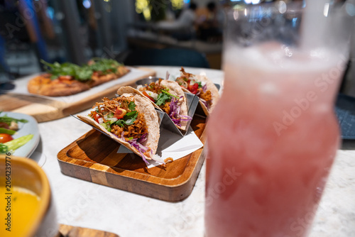 Obraz na plátně Colorful Tacos Served on Wooden Board with Pink Cocktail and Side Dishes in Mode