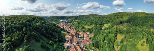 Malerische Luftaufnahme von Stolberg im Harz mit historischen Fachwerkhäusern, eingebettet in die grüne Berglandschaft mit Blick auf das Schloss. Perfekt für Tourismus und Reisen.