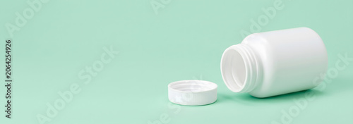 Open White Pill Bottle on Pastel Green Background.