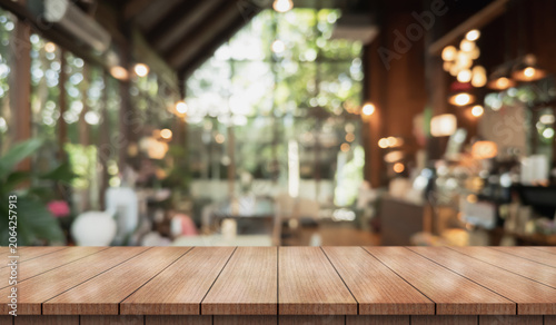 Empty wooden table top with lights bokeh on blur restaurant background.
