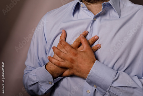 Foto Close up of a man in a blue shirt clutching his chest in distress