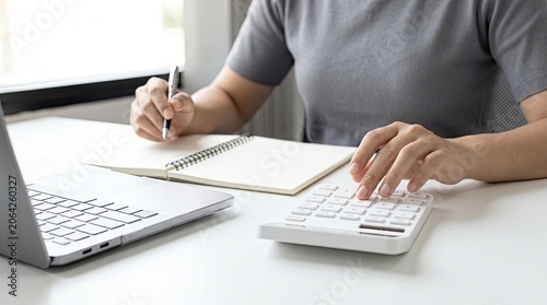Person working on finances with laptop and calculator.