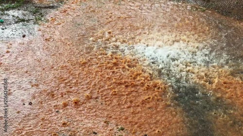 Heavy rainfall striking the ground and creating splashes on a wet surface, capturing the intensity and atmosphere of a monsoon downpour