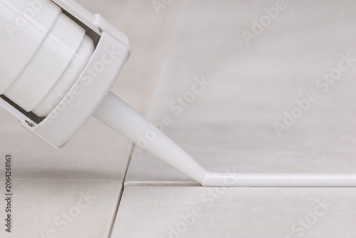 A caulk gun extruding a bead of sealant, close-up.